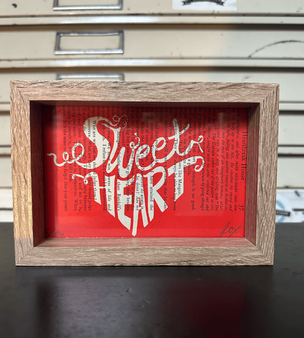 Sweet Heart screen print by Fox Fisher in wooden frame, white hand-lettering on red background printed on vintage book page, Fox's Snail Mail Art Club subscription art