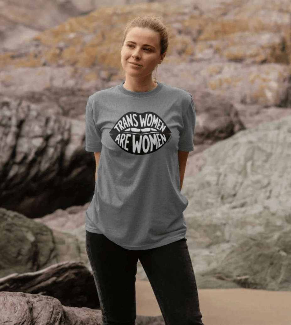 Model wearing grey Trans Women Are Women t-shirt outdoors on rocks by Fox Fisher, hand-drawn lips design organic cotton tee