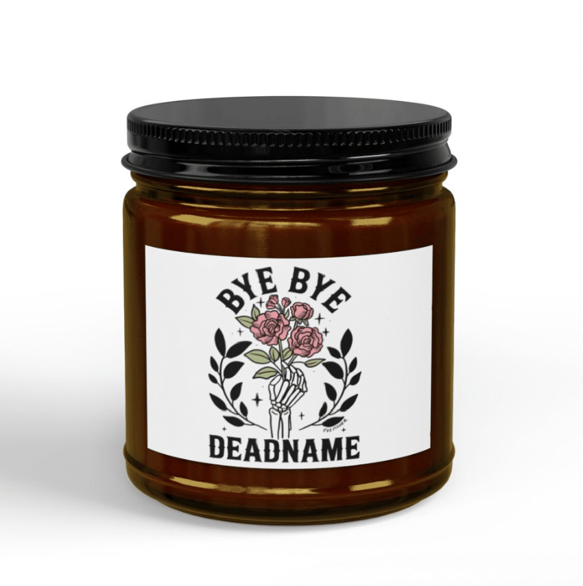 Bye Bye Deadname candle close-up, amber glass jar with black lid showing skeleton hand holding roses label design by Fox Fisher