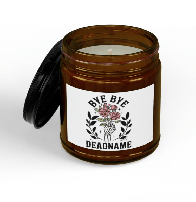 Bye Bye Deadname hand-poured soy candle in open amber jar showing Fox Fisher original skeleton and roses artwork label, trans-affirming gift